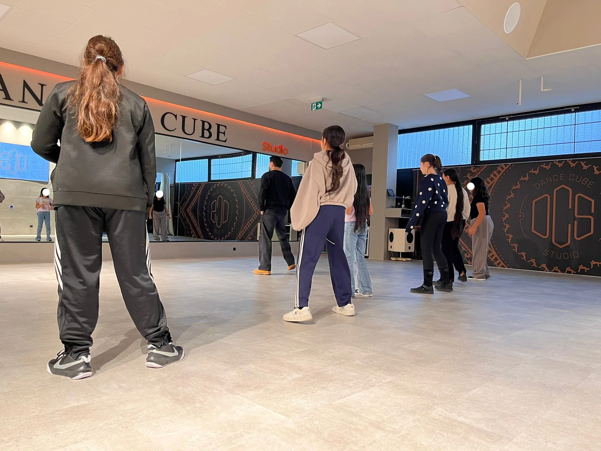 Jugendliche tanzen in einem modernen Tanzstudio mit großen Fenstern und Spiegeln. Im Hintergrund ist ein Schild. [gallerie-starke-stadt]